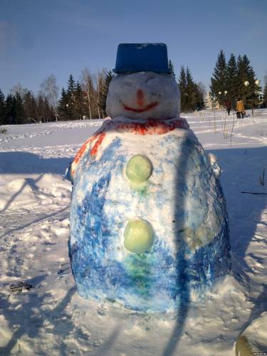 Снеговик со шлемом возле новогодней елки
